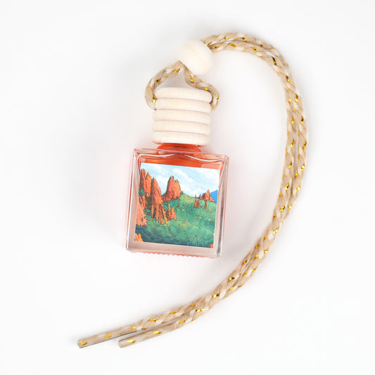 Artistic air freshener bottle with a colorful landscape design, featuring a braided rope for hanging.