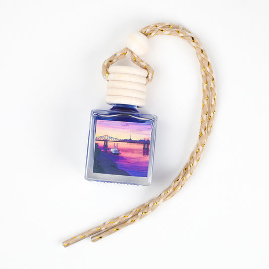 Blue car air freshener with scenic sunset image and braided hanging cord for stylish décor.