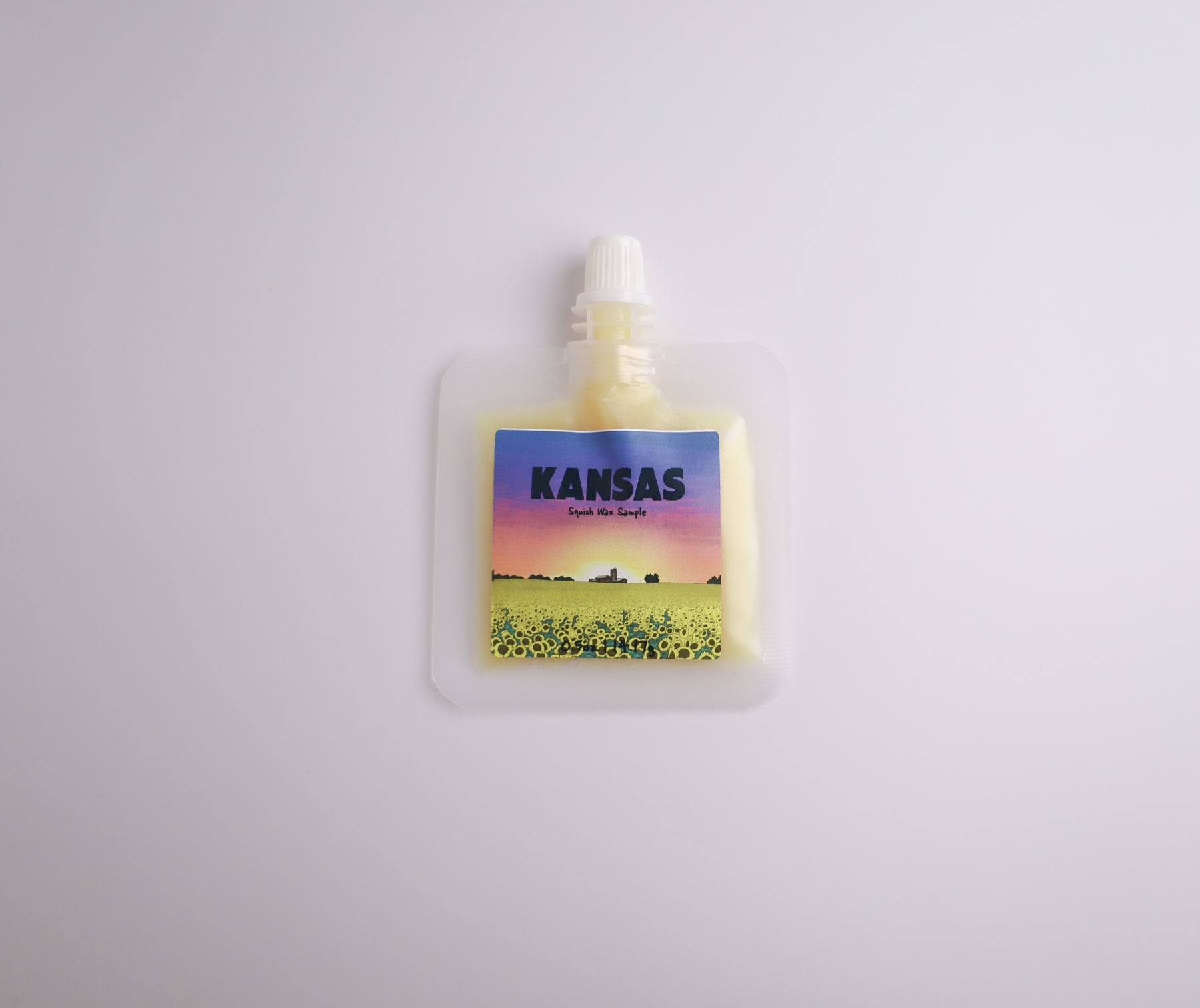 Small pouch with a colorful label featuring a landscape and the word 'Kansas' on a light gray background.