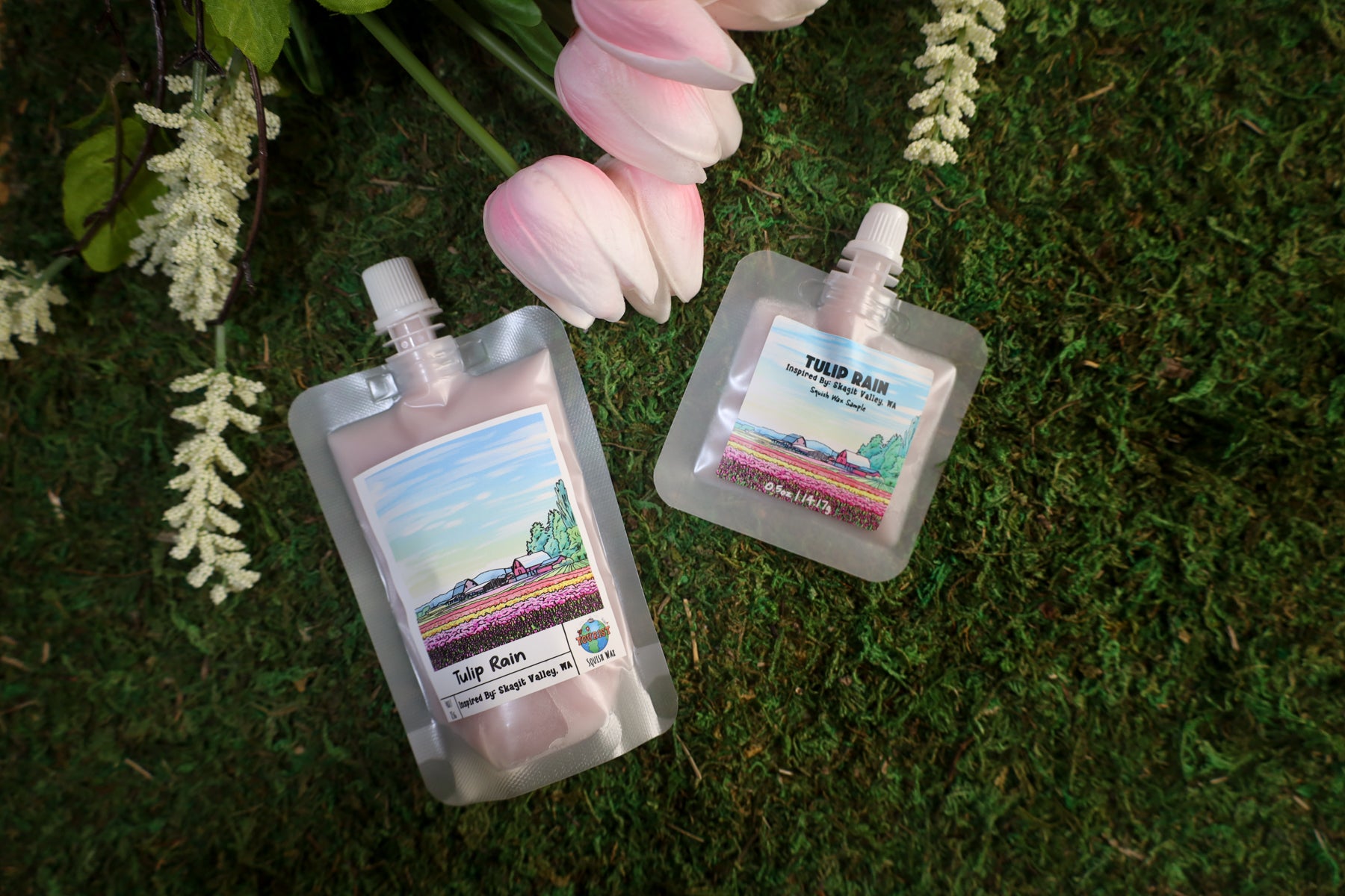 Two small pouches with labels on a green grass background with flowers.
