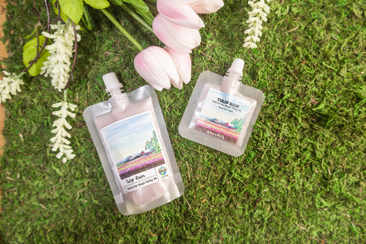 Two small pouches with labels on a green moss background with flowers.