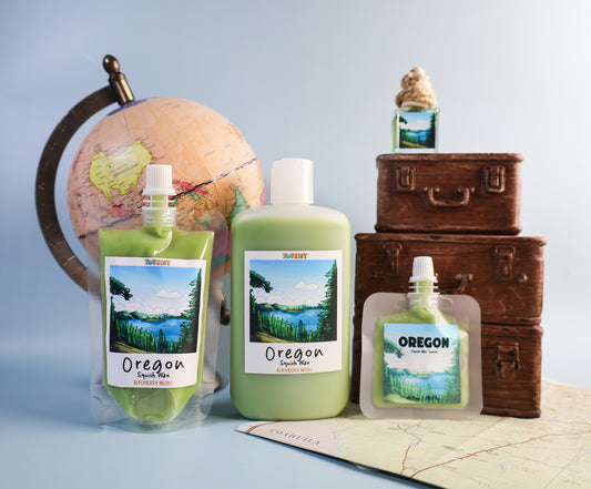 Oregon-themed squish wax products including bottles and a suitcase on a map with a globe in the background.