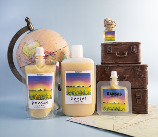 Three sizes squish wax labeled 'Kansas' with a globe and suitcases in the background on a light blue background