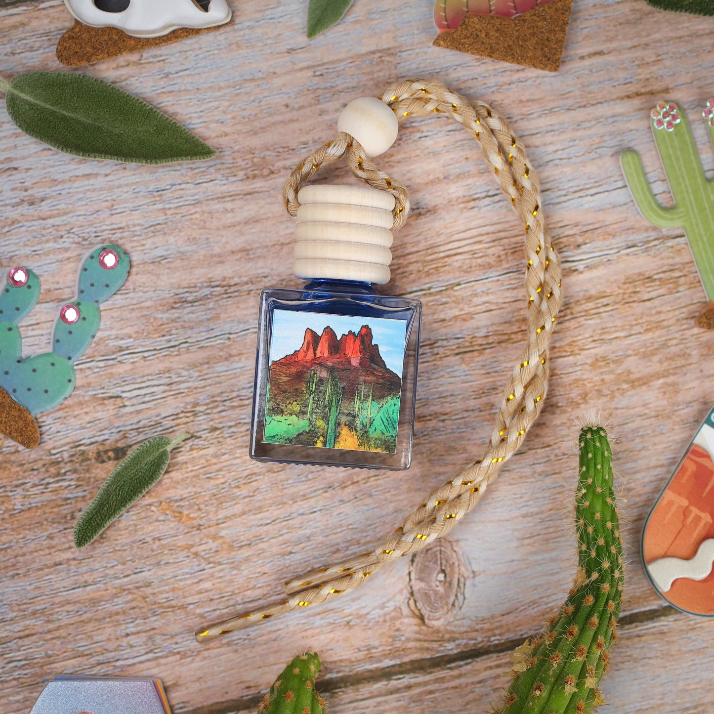 A blue glass car air freshener with cactus design and wood stopper, featuring a braided rope.
