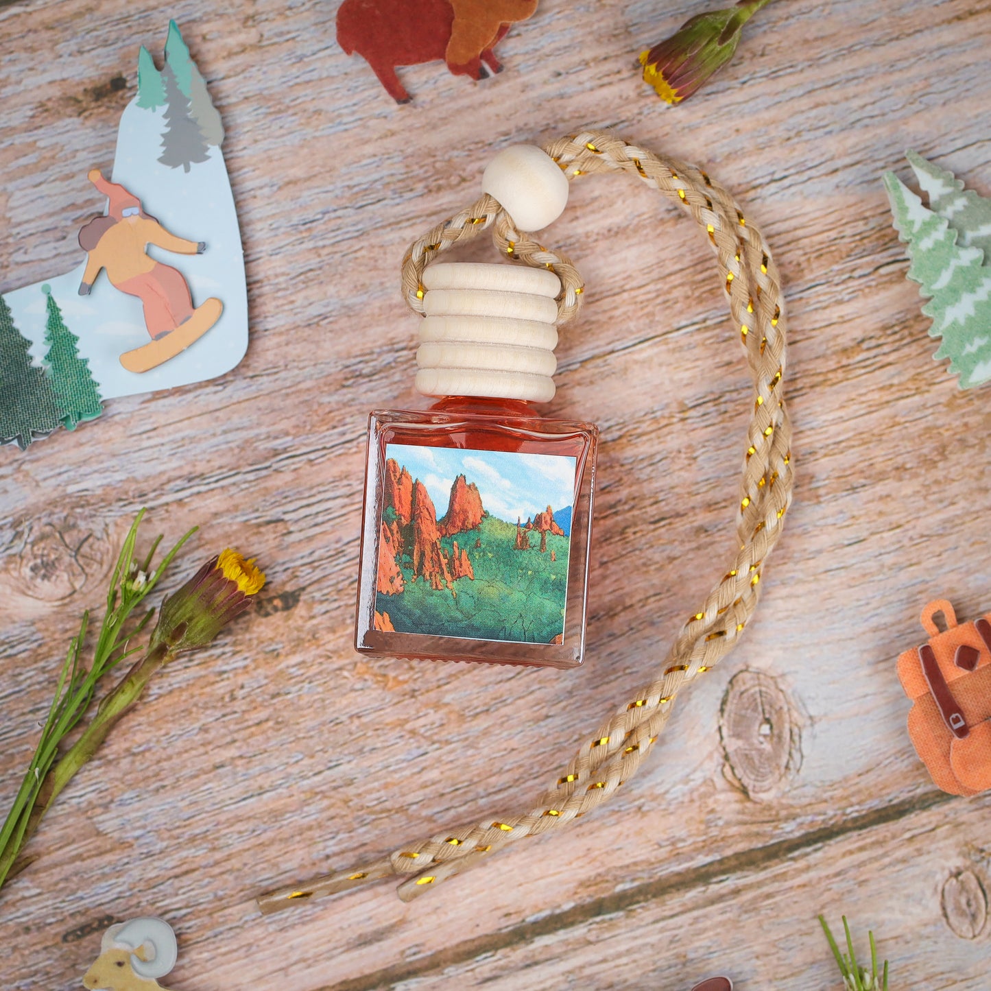 Elegant forest-themed air freshener, square glass bottle with braided rope, vibrant landscape design.