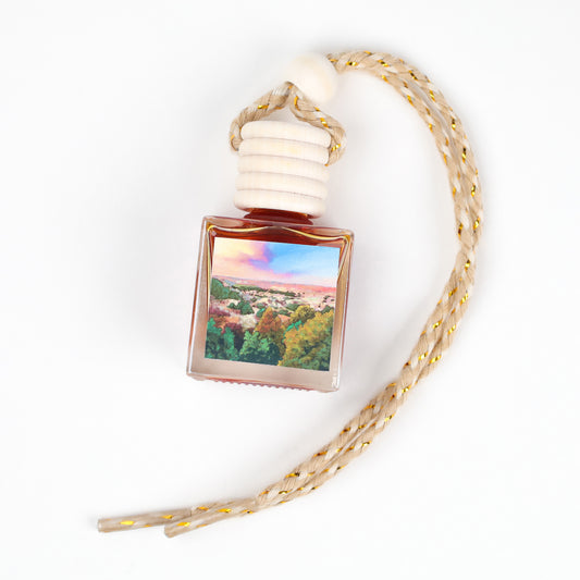 Elegant car diffuser in amber glass with a scenic label and natural wood cap, designed for aromatherapy.