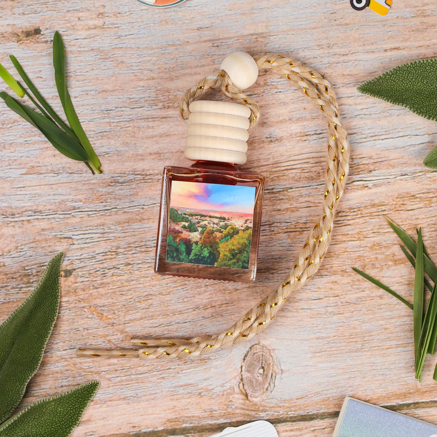 Amber glass car air freshener with wood cap and outdoor landscape label, ideal for refreshing car interiors.