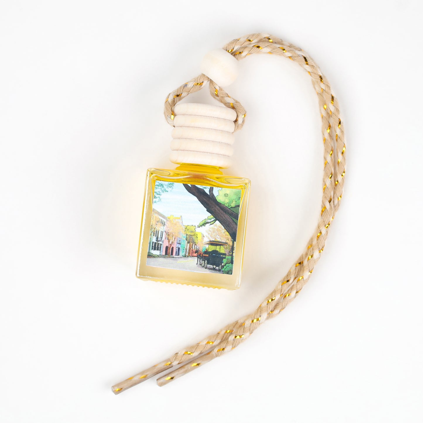 Yellow scented car air freshener with decorative bottle and braided cord, featuring a street scene design.