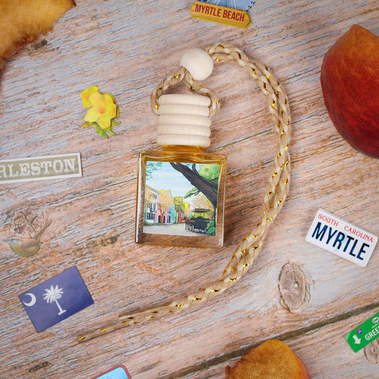 A scented car air freshener with a wooden top, featuring a Charleston scene on the bottle, braided cord.