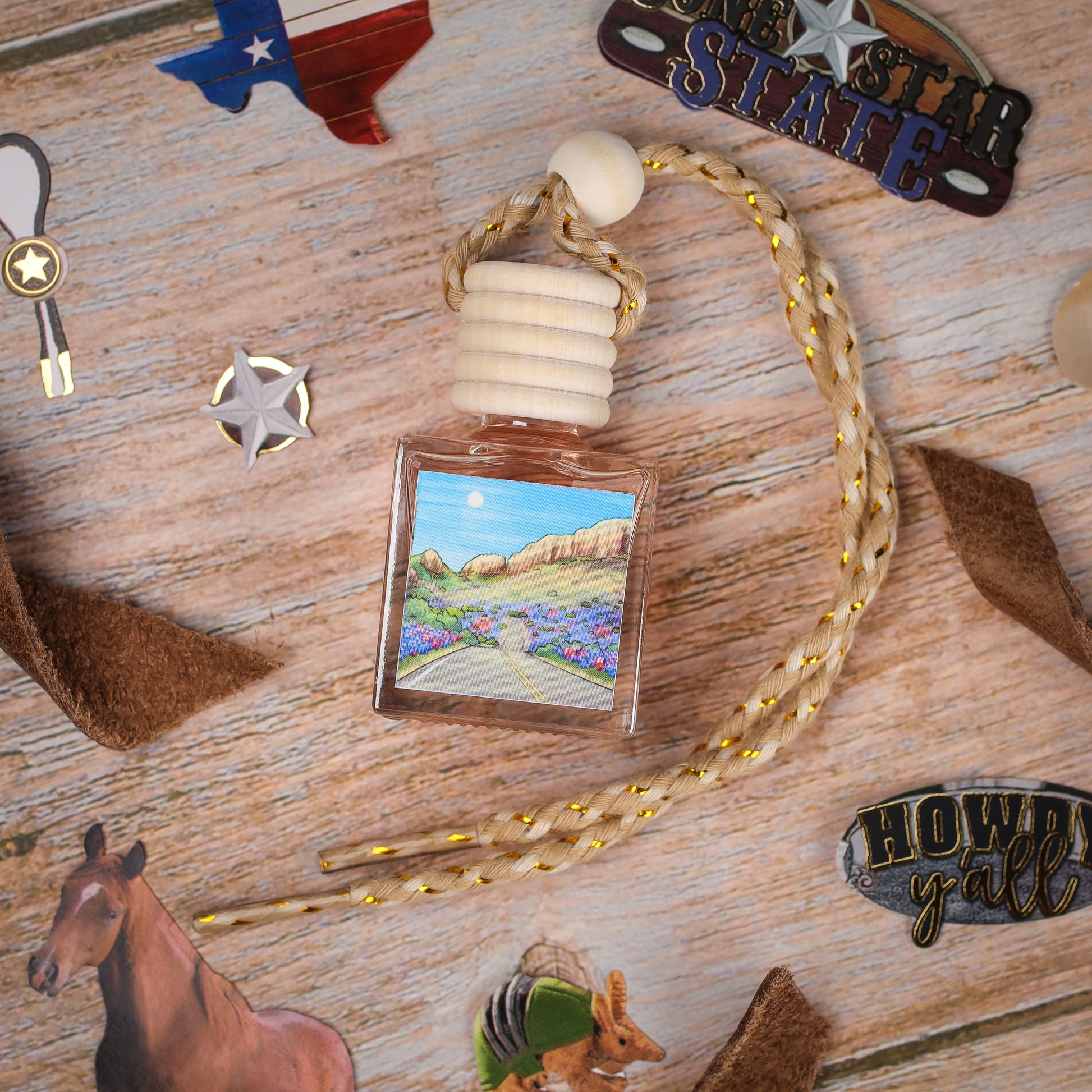 Texas-themed air freshener, square glass bottle with scenic landscape, wooden cap, and braided rope.