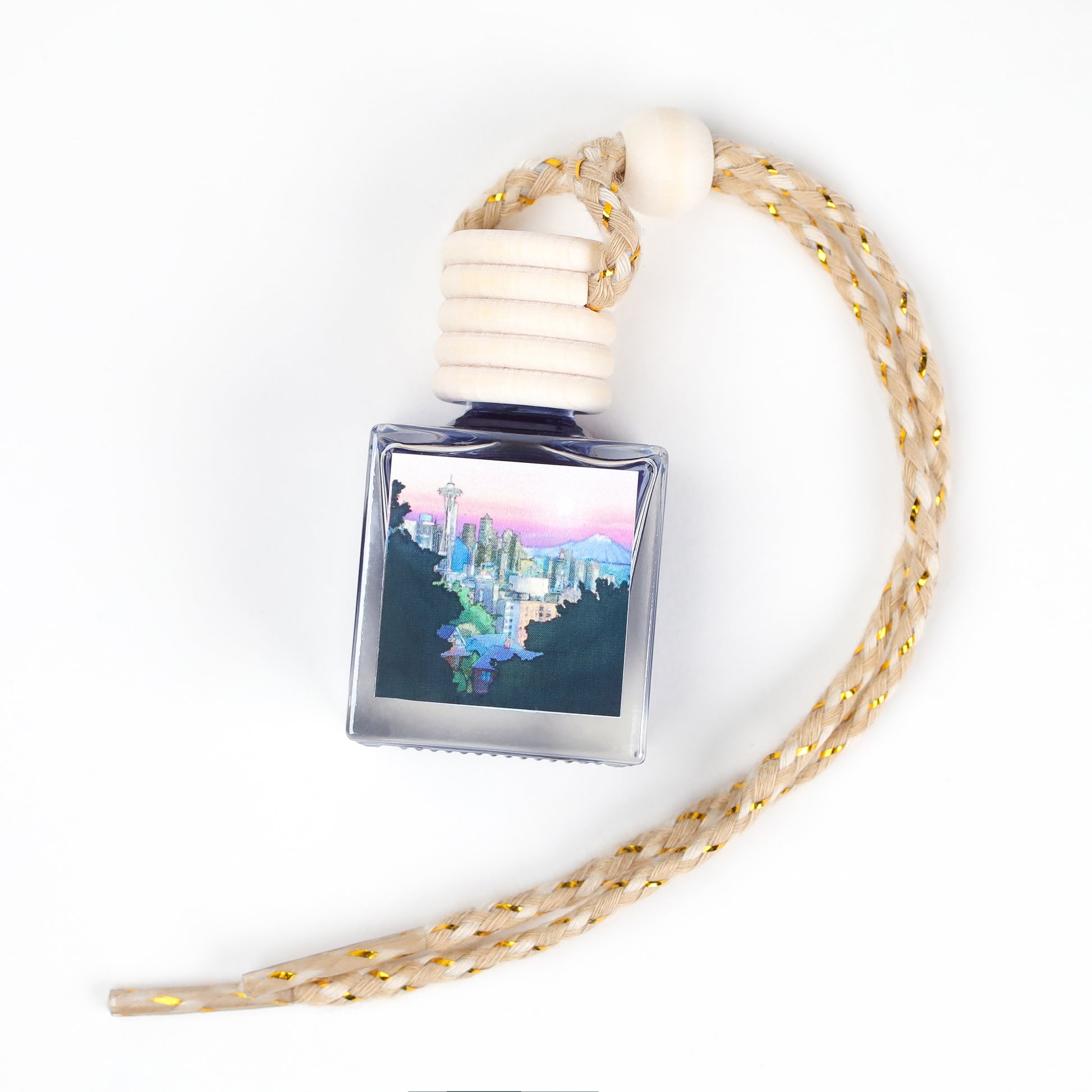 A blue glass fragrance bottle with a wooden cap and braided rope, featuring a cityscape design.