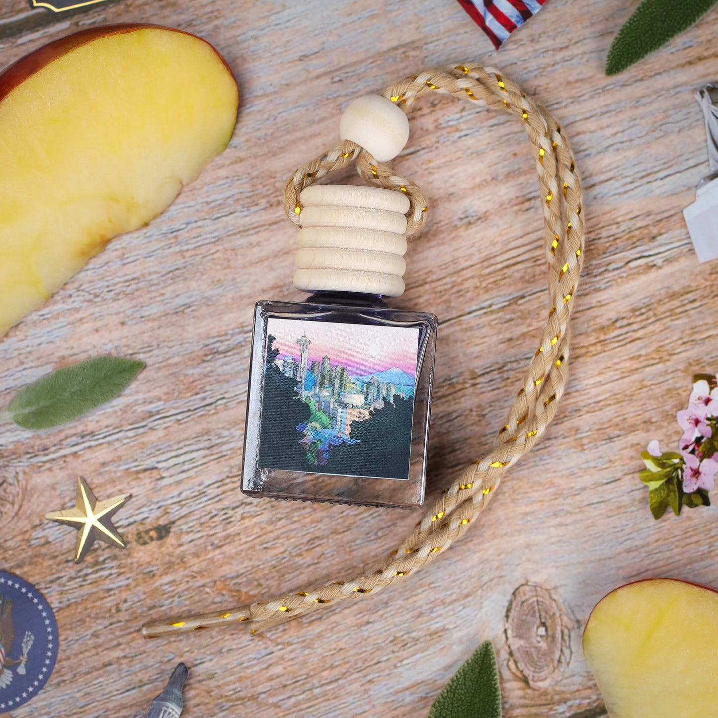 Scented car air freshener in a glass bottle, with a wooden cap and cityscape design, featuring a braided cord.