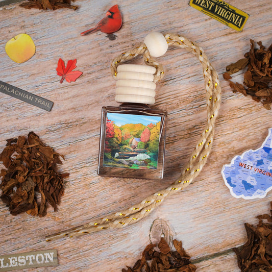 Handcrafted car air freshener, square glass bottle, nature artwork design, featuring fall colors and wooden cap.